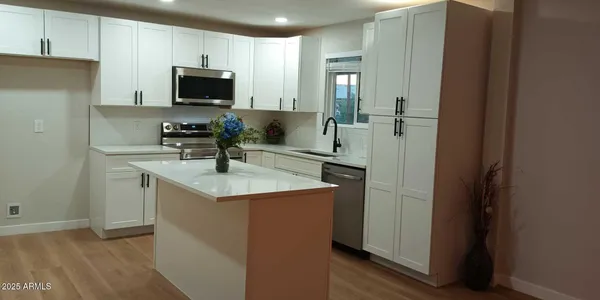 a kitchen with stainless steel appliances a sink a stove a microwave a refrigerator a sink and cabinets