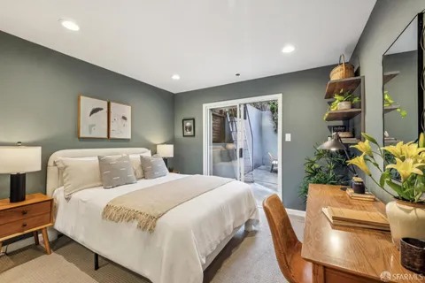 a bedroom with a bed mirror and painting on the wall