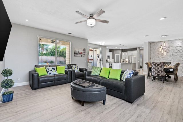 a kitchen with stainless steel appliances granite countertop a sink a microwave oven a refrigerator and white cabinets with wooden floor