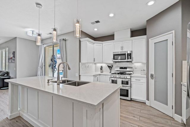 a kitchen with granite countertop a sink stainless steel appliances and cabinets