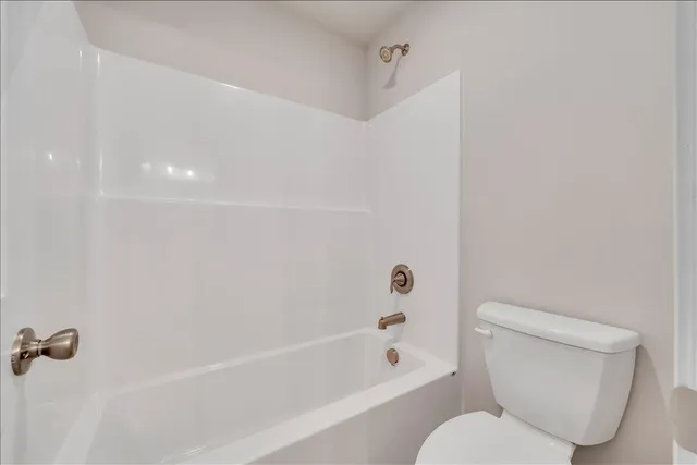 a white toilet sitting next to a bath tub