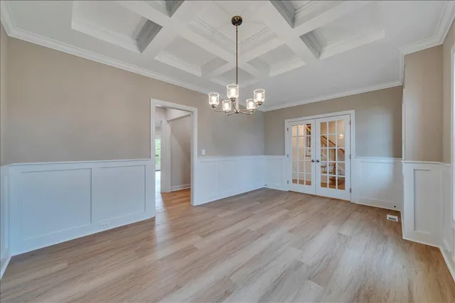 an empty room with wooden floor chandelier and windows