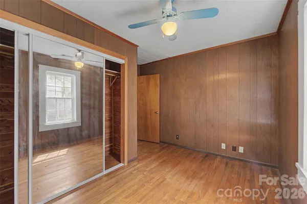 a view of empty room with wooden floor and fan