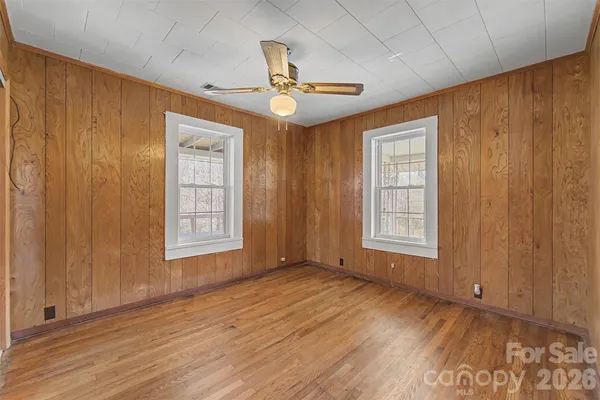a view of an empty room with a window and wooden floor