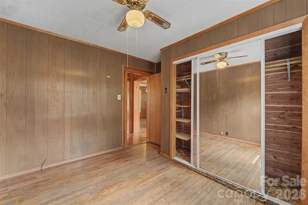 an empty room with wooden floor mirror and windows