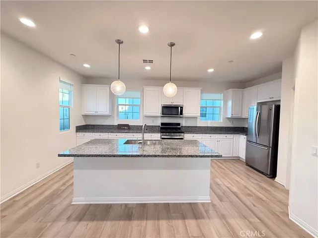 a large kitchen with granite countertop a sink a counter top space appliances and cabinets