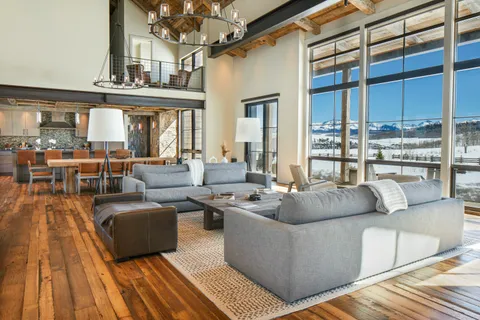 a living room with couches a dining table and chairs with wooden floor