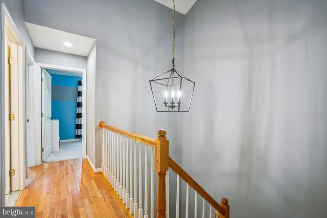 a view of a hallway with wooden floor and chandelier