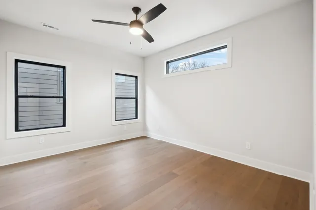 a view of an empty room with a window and a ceiling fan