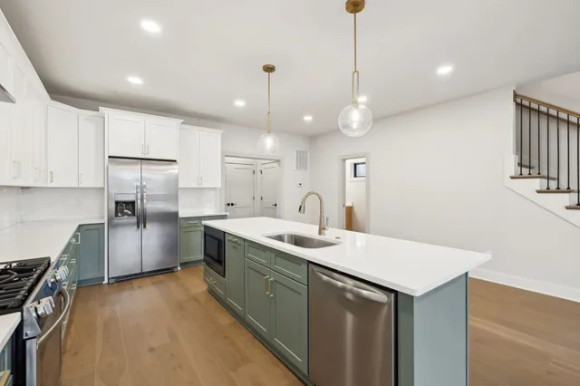 a kitchen with kitchen island a sink stainless steel appliances and a counter top space