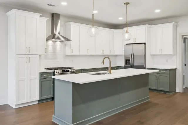 a kitchen with stainless steel appliances granite countertop a sink a stove a refrigerator and island with wooden floor