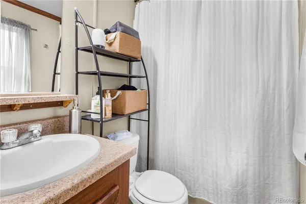 a bathroom with a granite countertop sink toilet and mirror