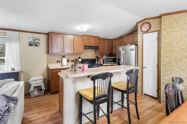 a kitchen with stainless steel appliances a refrigerator a stove a sink dishwasher and a dining table with wooden floor