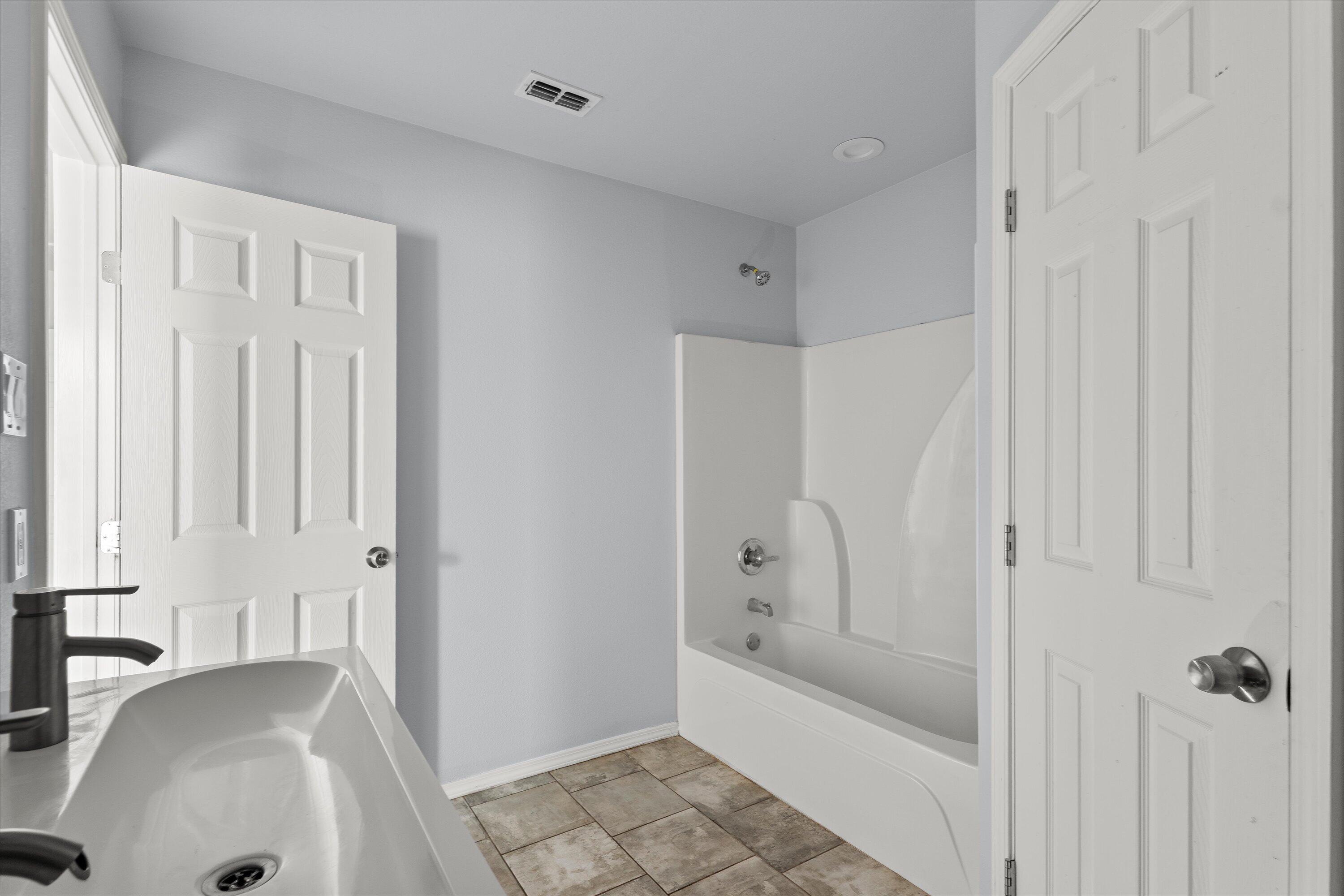 8414 11th Street Lubbock, TX 79416 - Photo 17 of 26 a bathroom with a tub shower and sink