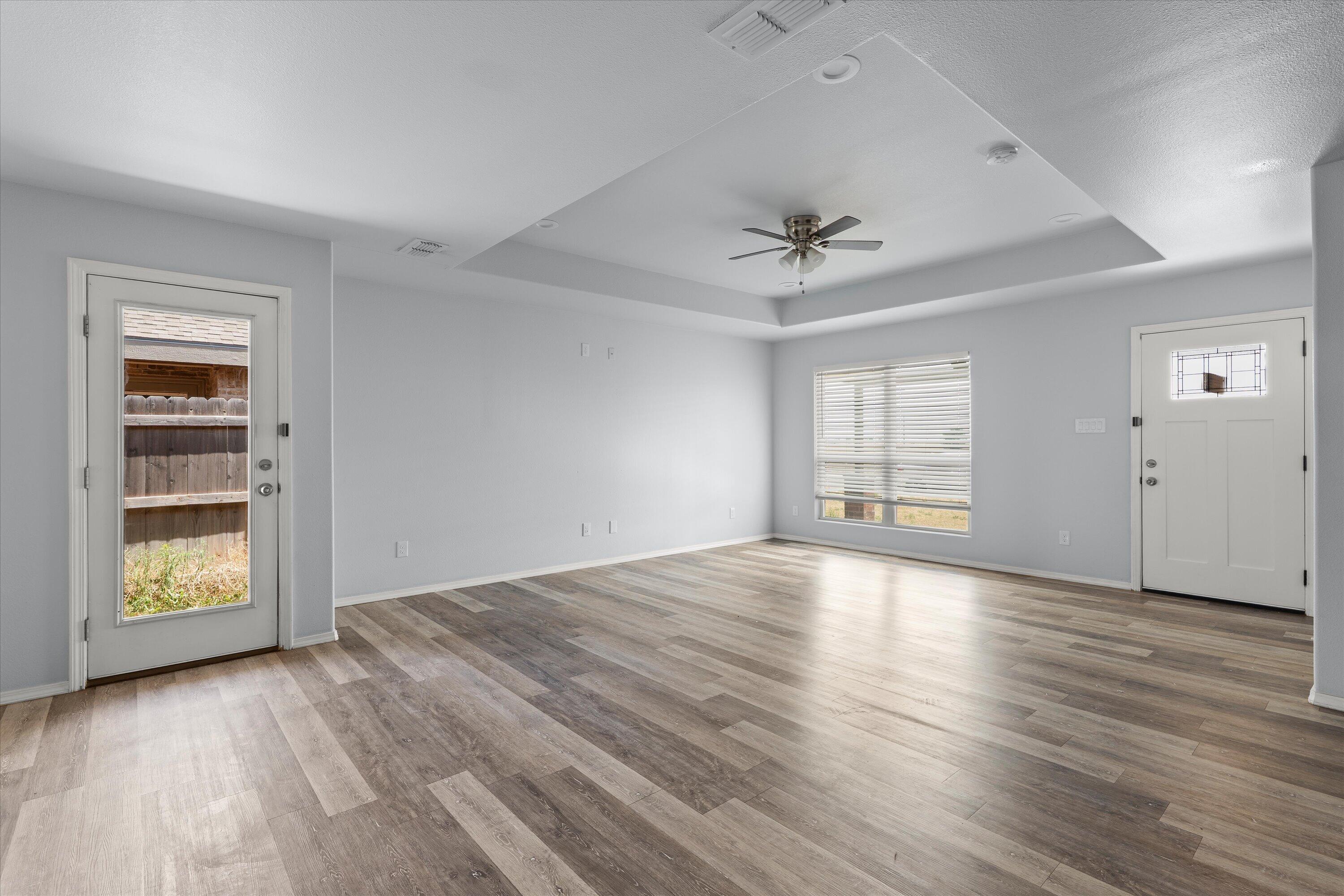 8414 11th Street Lubbock, TX 79416 - Photo 7 of 26 an empty room with wooden floor chandelier and windows