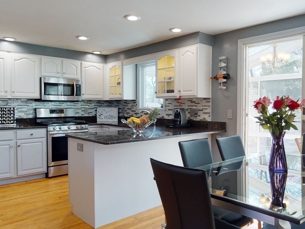 30 Kingston Road Waltham, MA 02451 - Photo 14 of 41 a kitchen with stainless steel appliances granite countertop a stove top oven a sink a dining table and chairs