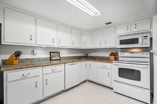 a kitchen with granite countertop white cabinets and stainless steel appliances