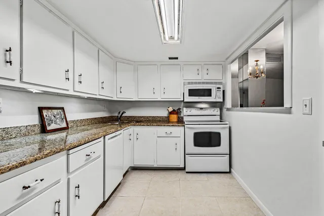 a kitchen with granite countertop white cabinets and white appliances