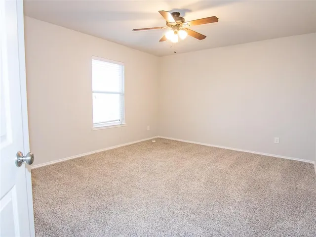 an empty room with a window and a fan