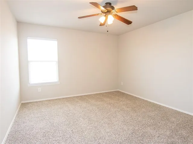 an empty room with a window and a fan
