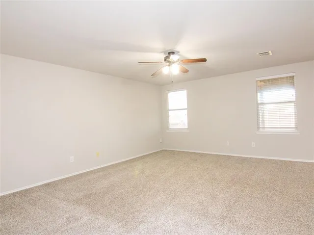 an empty room with windows and ceiling fan