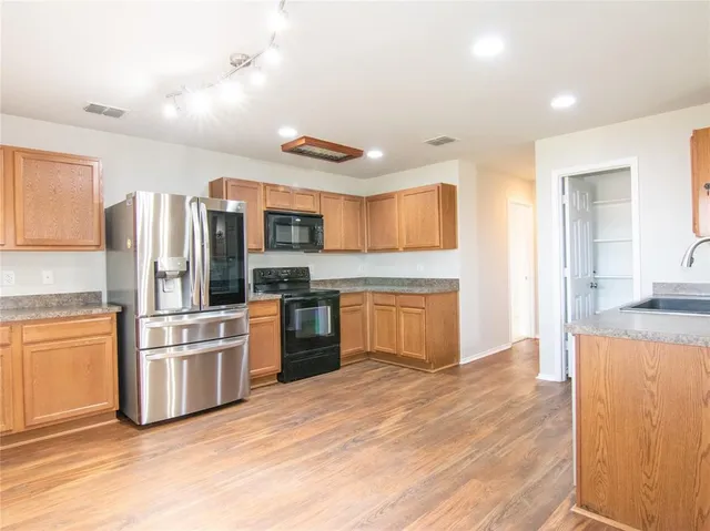 a kitchen with stainless steel appliances granite countertop a refrigerator and a stove top oven