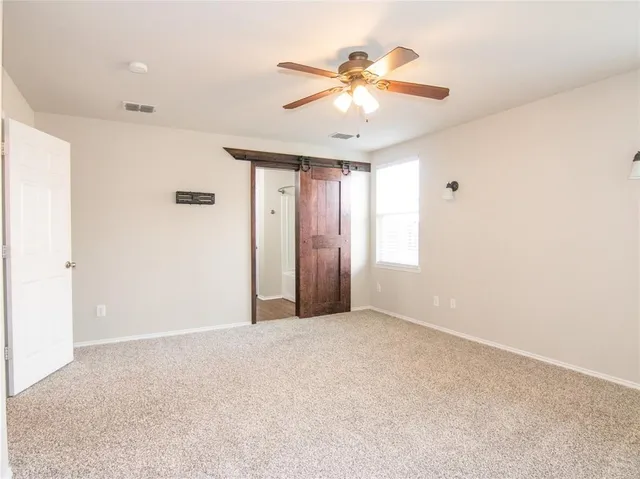 a view of an empty room with chandelier fan