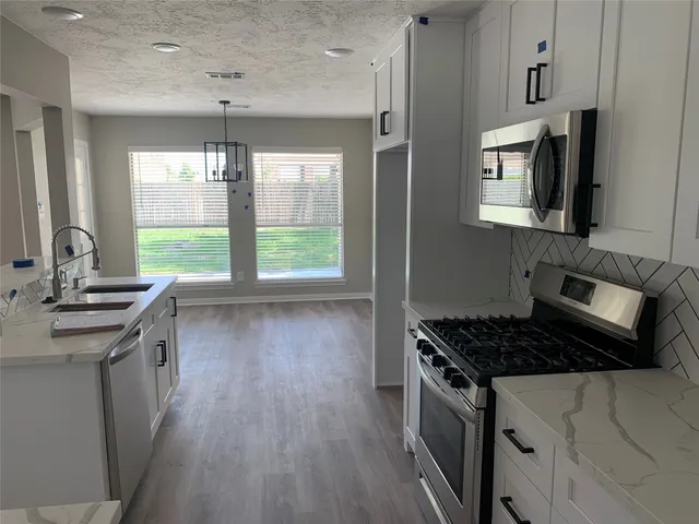 a kitchen with stainless steel appliances granite countertop a stove a sink dishwasher and a microwave oven with wooden floor