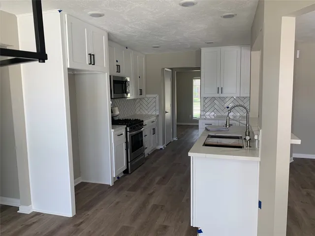 a kitchen with stainless steel appliances granite countertop a refrigerator stove and white cabinets
