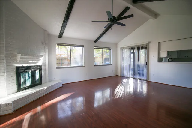 a view of an empty room with wooden floor fireplace and a window