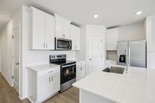 a kitchen with granite countertop a refrigerator stove a sink dishwasher and microwave with wooden cabinets