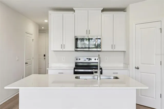 a kitchen with stainless steel appliances a stove a microwave and a white cabinets