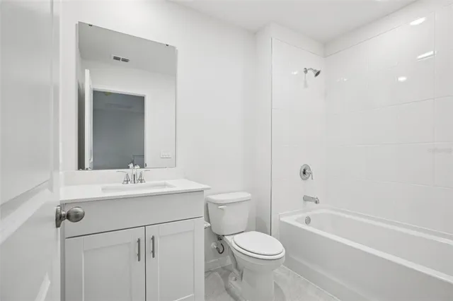 a bathroom with a toilet a sink a mirror a bathtub and vanity