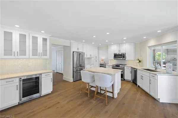 a kitchen with stainless steel appliances granite countertop a stove top oven a sink dishwasher a dining table and chairs with wooden floor