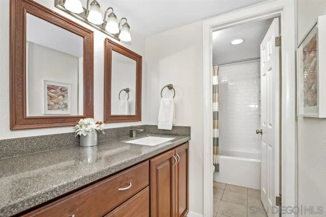 a bathroom with a granite countertop sink a mirror a vanity and shower
