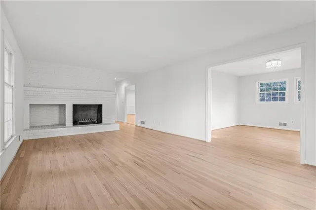 a view of empty room with wooden floor and fireplace