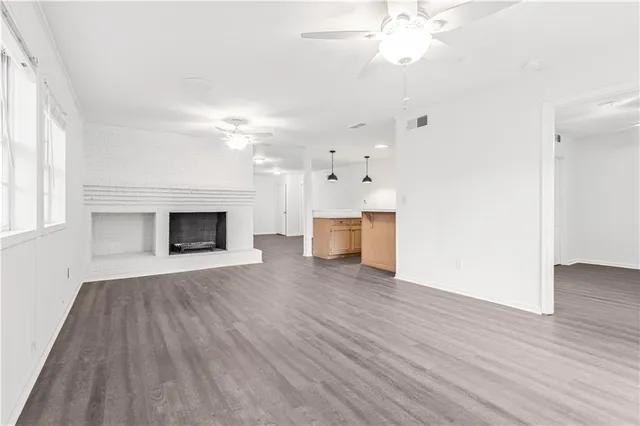 an empty room with wooden floor fireplace and windows