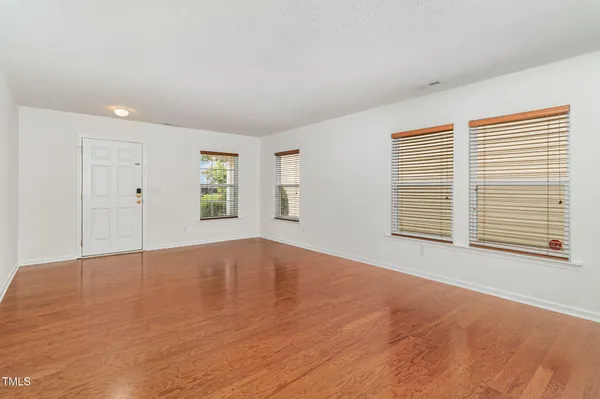 a view of an empty room with a window and wooden floor