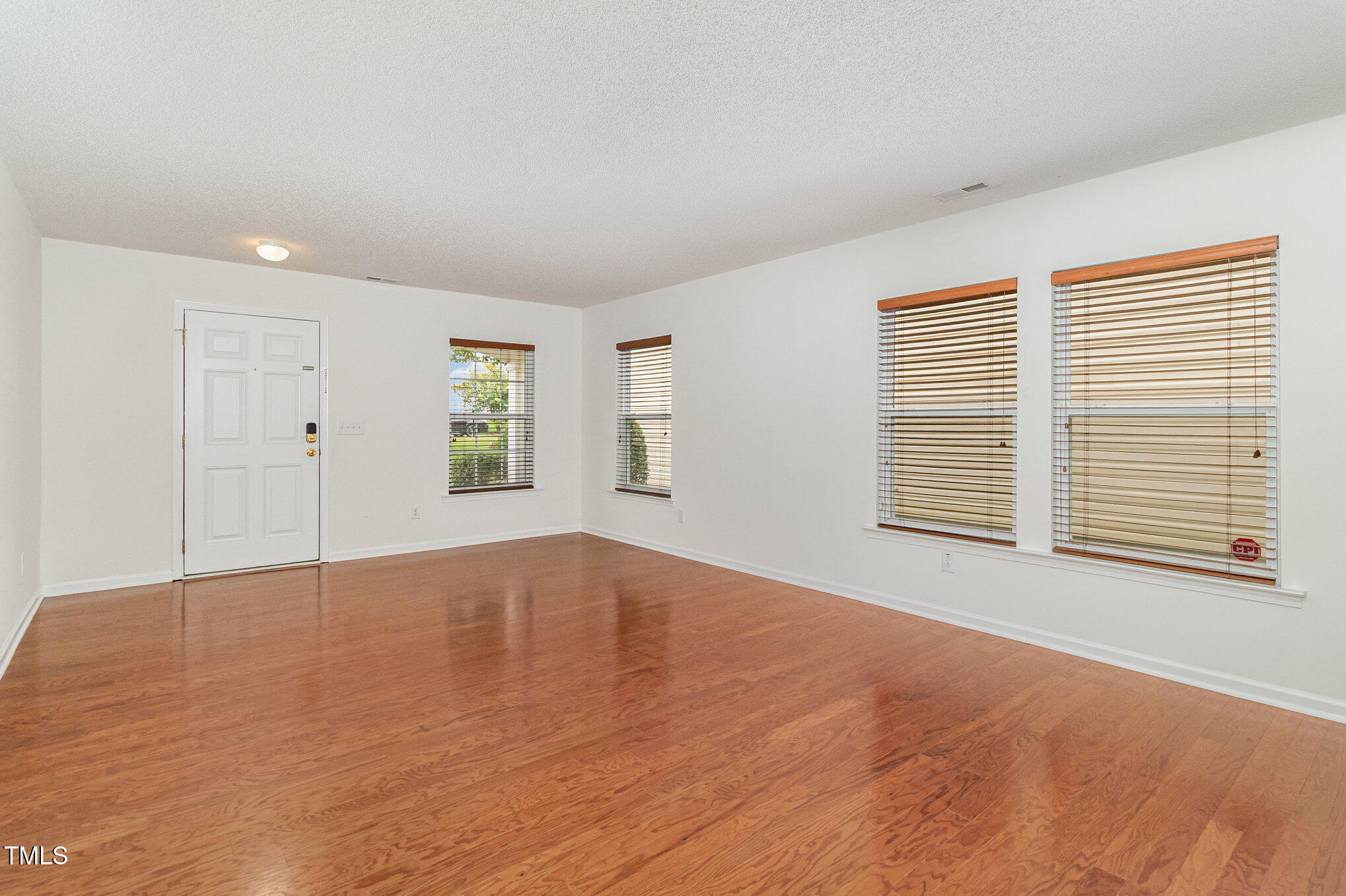 5404 Meryton Park Way Raleigh, NC 27616 - Photo 9 of 35 a view of an empty room with a window and wooden floor