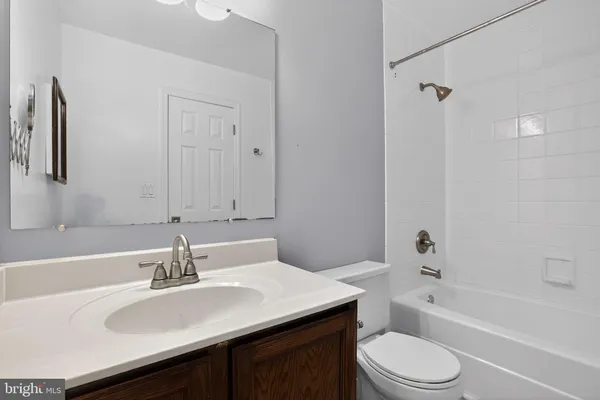 a bathroom with a bathtub shower sink vanity mirror and toilet