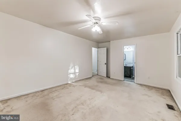 an empty room with chandelier fan and windows