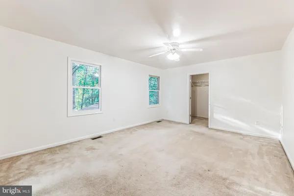 an empty room with windows and fan