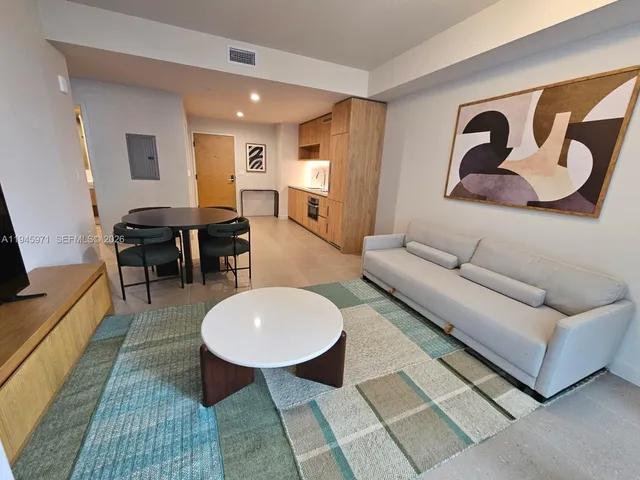 a living room with couches a dining table and kitchen view with wooden floor