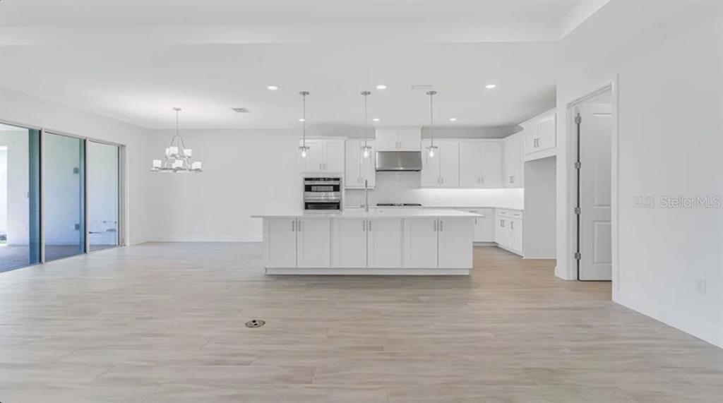 899 Arbor Grn Trail St. Cloud, FL 34771 - Photo 16 of 34 a large white kitchen with kitchen island white cabinets and stainless steel appliances