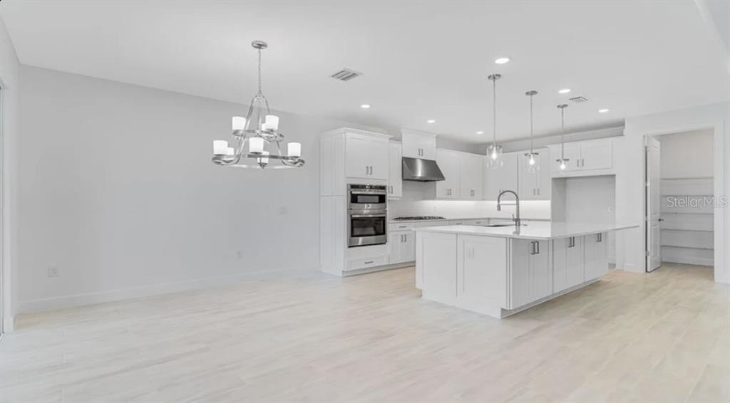 899 Arbor Grn Trail St. Cloud, FL 34771 - Photo 3 of 34 a large white kitchen with white cabinets and stainless steel appliances