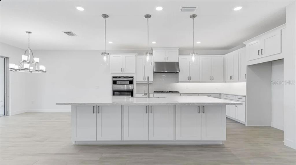899 Arbor Grn Trail St. Cloud, FL 34771 - Photo 6 of 34 a large kitchen with kitchen island a sink stainless steel appliances and cabinets