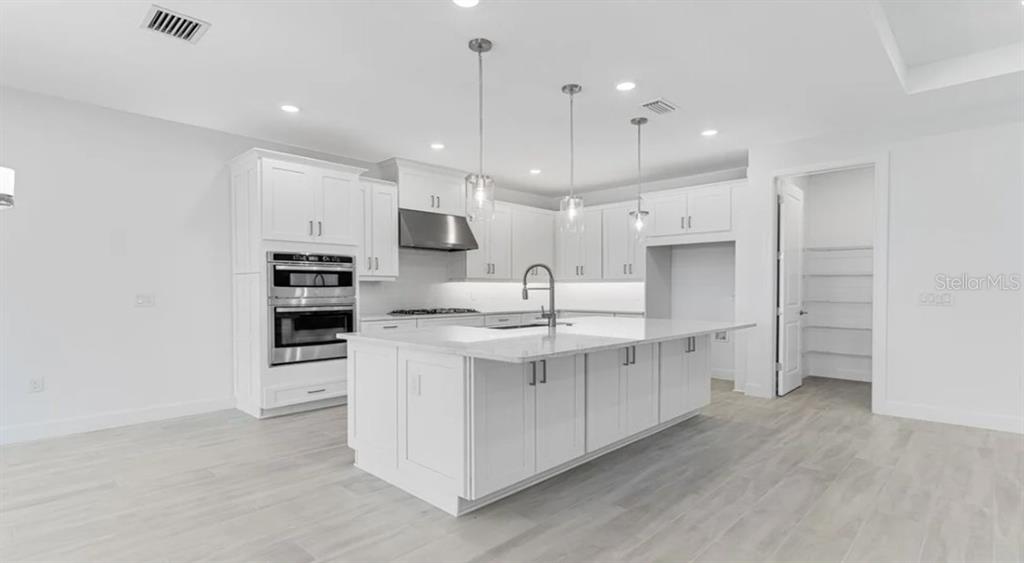 899 Arbor Grn Trail St. Cloud, FL 34771 - Photo 7 of 34 a kitchen with stainless steel appliances kitchen island a refrigerator sink and cabinets
