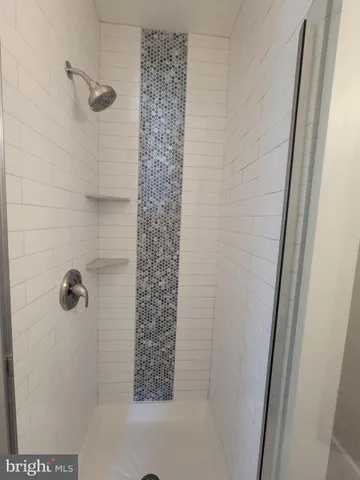an empty room with stainless steel appliances wooden floor and a kitchen view
