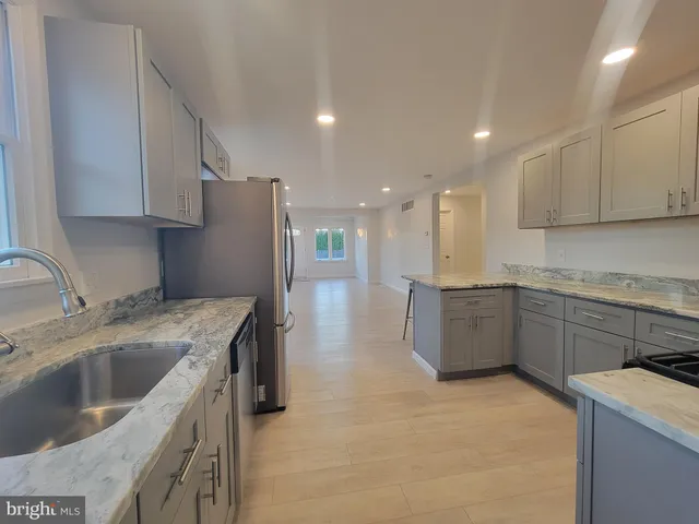 a kitchen with stainless steel appliances granite countertop a sink a refrigerator and a stove