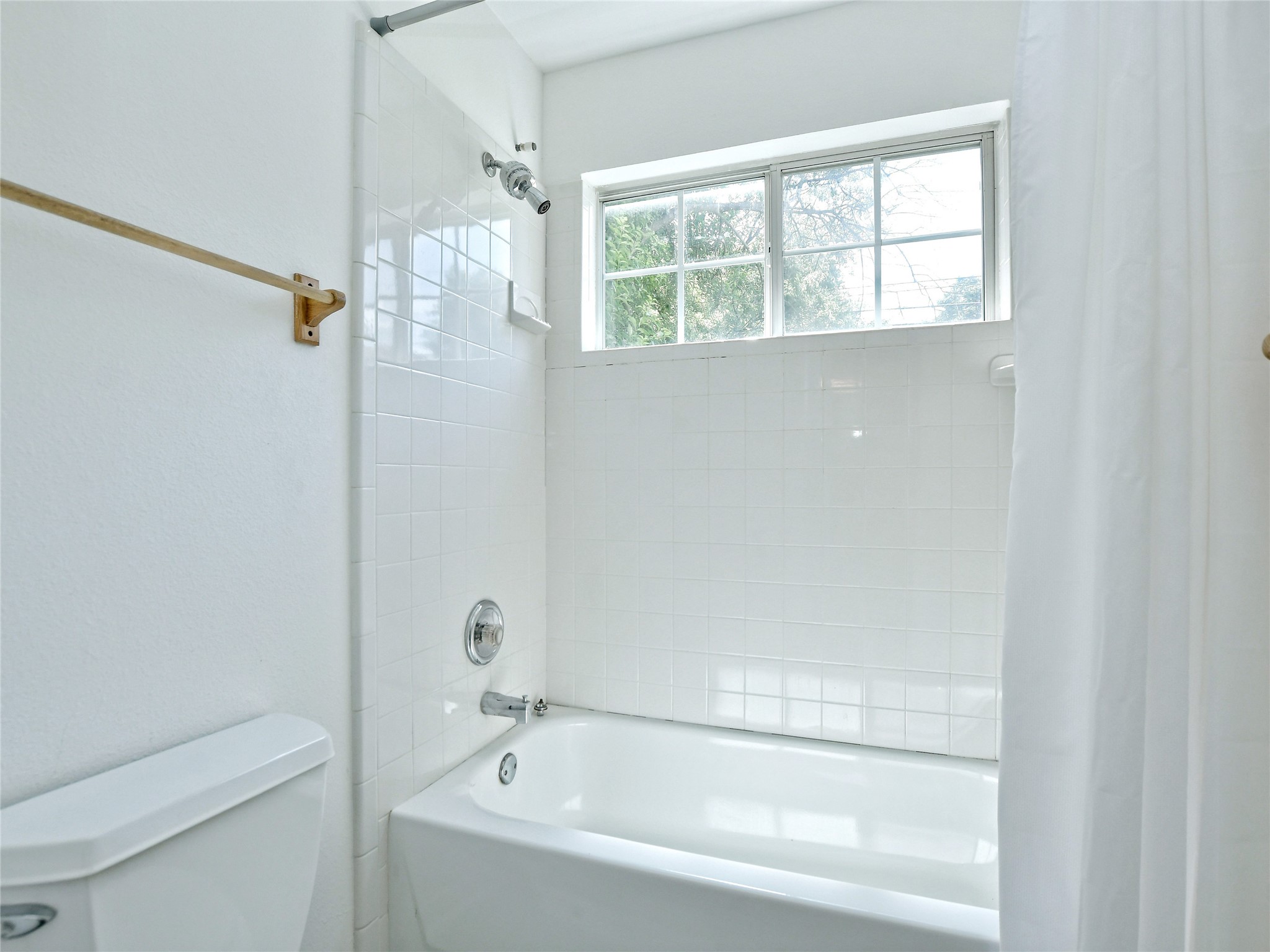 4604 Red River Street, Unit A Austin, TX 78751 - Photo 10 of 15 White tiled shower and bathtub combination featuring a chrome showerhead and faucet